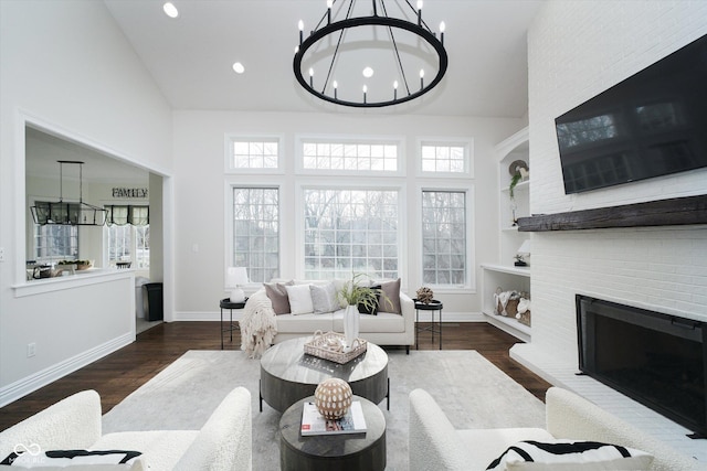 living room with a brick fireplace, high vaulted ceiling, dark hardwood / wood-style floors, and a chandelier