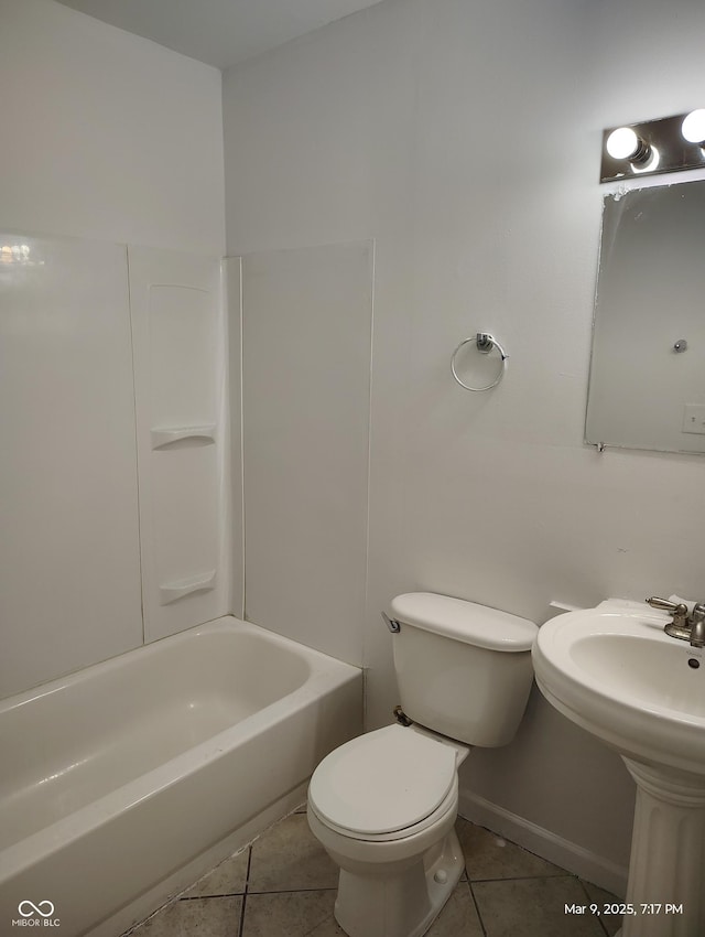 bathroom with baseboards, toilet, bathing tub / shower combination, tile patterned floors, and a sink