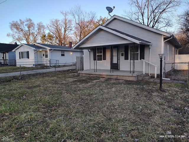 bungalow with a porch, a front yard, and fence