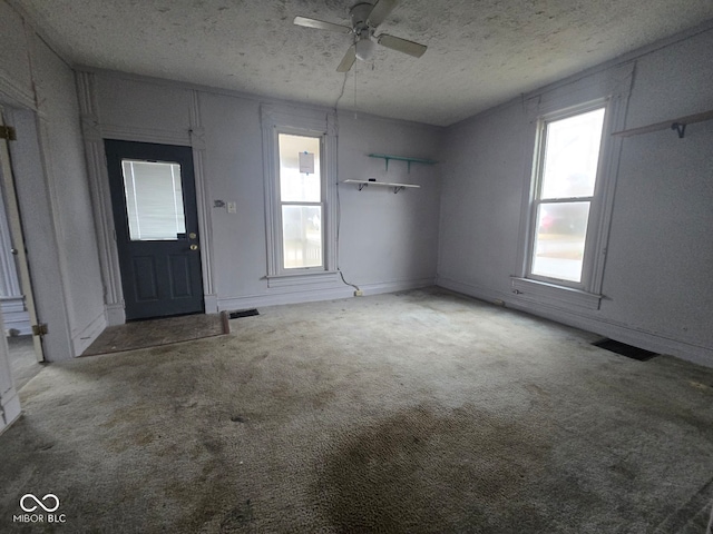 foyer entrance with ceiling fan, carpet, and a textured ceiling