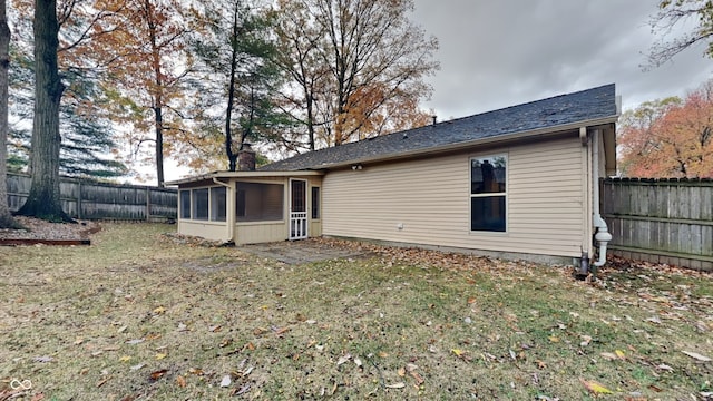 rear view of property featuring a lawn and a sunroom