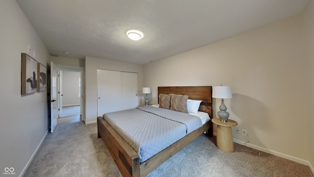 bedroom with a closet, light carpet, and a textured ceiling