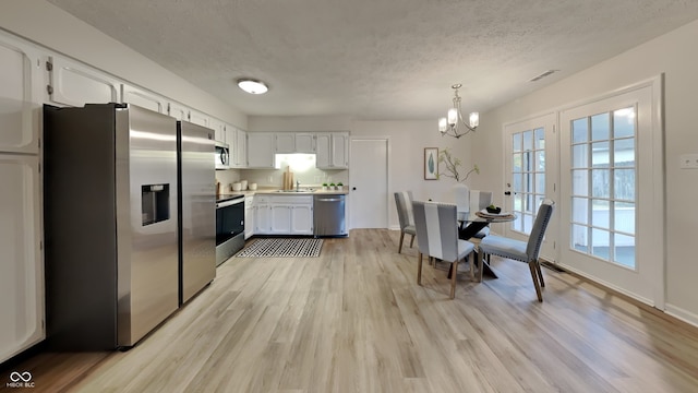 dining space with an inviting chandelier, sink, a textured ceiling, and light wood-type flooring