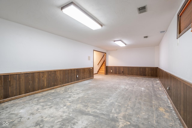 unfurnished room featuring concrete floors and wooden walls