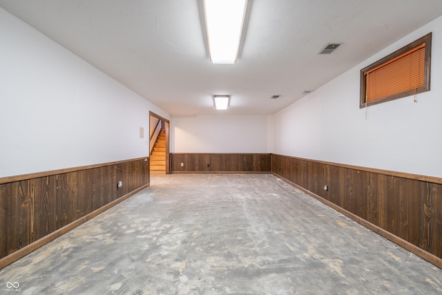 spare room featuring wooden walls and concrete floors