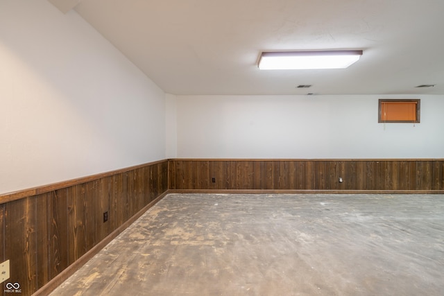 empty room featuring concrete floors and wood walls