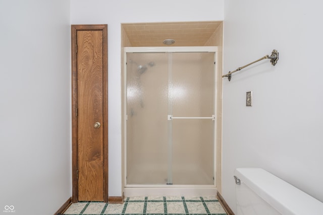 bathroom with a shower with door and toilet