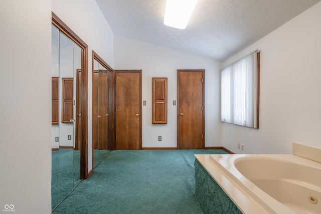 bathroom with lofted ceiling, a textured ceiling, and a tub to relax in