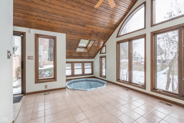 interior space with light tile patterned floors, wood ceiling, a wealth of natural light, and a skylight