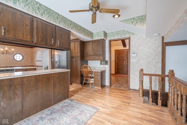 kitchen with dark brown cabinetry, ceiling fan with notable chandelier, light wood-type flooring, and decorative backsplash