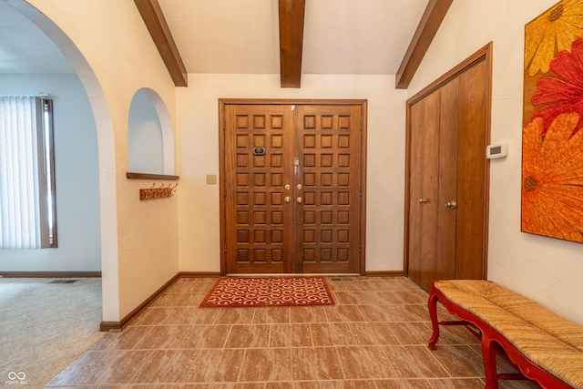 foyer featuring beamed ceiling and carpet