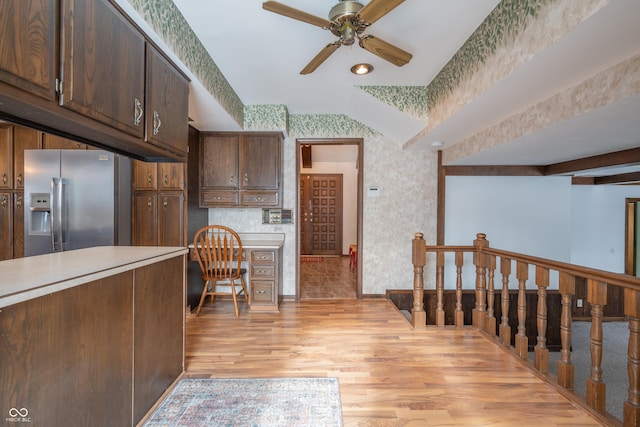 kitchen with built in desk, stainless steel fridge with ice dispenser, dark brown cabinets, light wood-type flooring, and ceiling fan