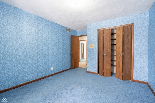 unfurnished bedroom featuring a closet, carpet, and a textured ceiling