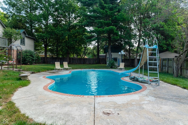 view of swimming pool featuring a yard, a water slide, and a patio