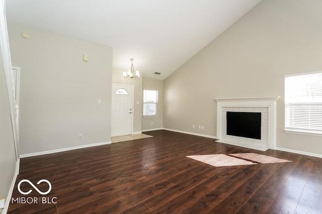 unfurnished living room featuring a fireplace, dark hardwood / wood-style flooring, high vaulted ceiling, and a notable chandelier