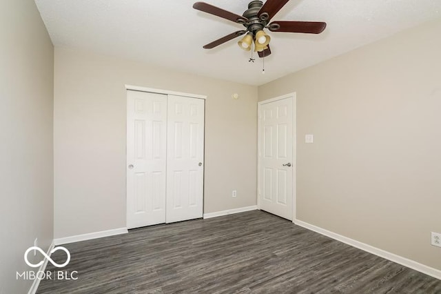 unfurnished bedroom with dark wood-type flooring, ceiling fan, and a closet