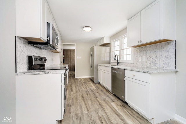 kitchen with stainless steel appliances, sink, white cabinets, and light hardwood / wood-style floors