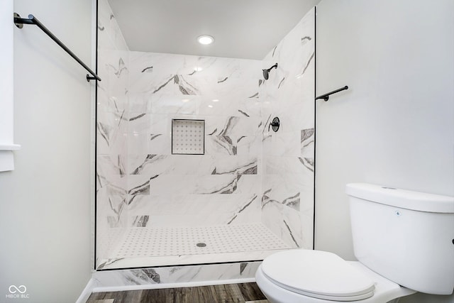 bathroom with a tile shower, wood-type flooring, and toilet