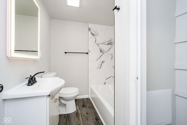 full bathroom featuring hardwood / wood-style flooring, tiled shower / bath, vanity, and toilet