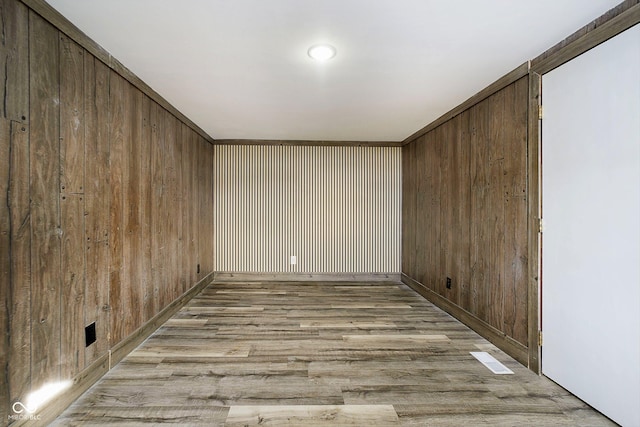 empty room with light wood-type flooring and wood walls