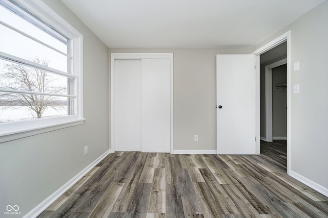 unfurnished bedroom with dark hardwood / wood-style flooring and a closet