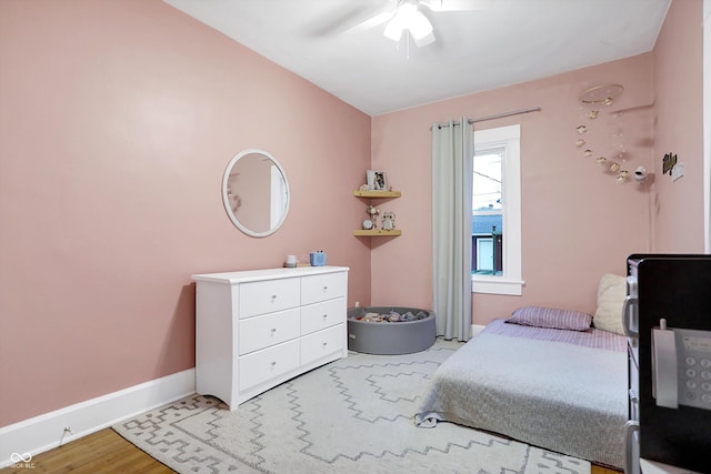 bedroom featuring ceiling fan, light wood-style floors, and baseboards