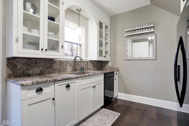 kitchen with tasteful backsplash, glass insert cabinets, a sink, and light stone countertops