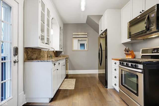 kitchen with dark wood-style floors, black appliances, a sink, and glass insert cabinets