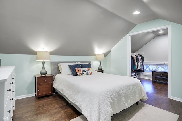 bedroom with a spacious closet, baseboards, vaulted ceiling, and wood finished floors