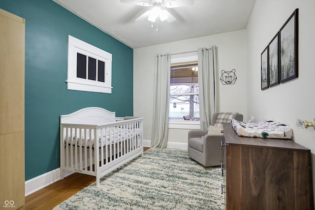 bedroom featuring a crib, a ceiling fan, and baseboards