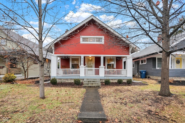 bungalow-style home with a front yard and covered porch