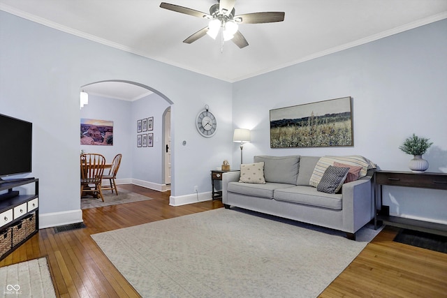 living room with arched walkways, crown molding, wood-type flooring, and baseboards