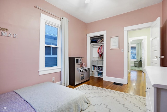 bedroom featuring multiple windows, wood-type flooring, visible vents, and baseboards