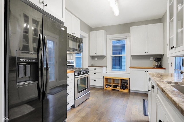 kitchen with black appliances, hardwood / wood-style floors, white cabinetry, and light stone counters