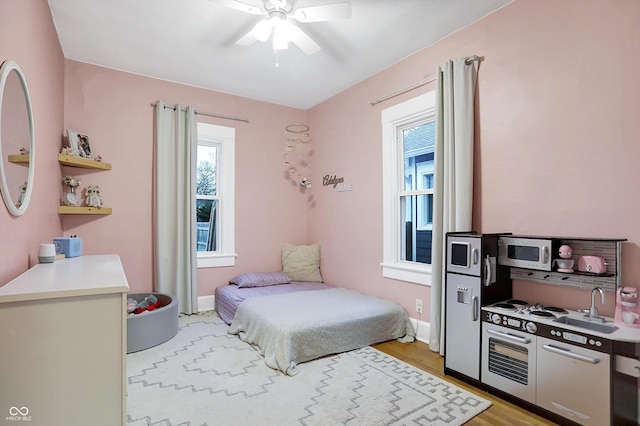 bedroom featuring ceiling fan, light wood-type flooring, and baseboards