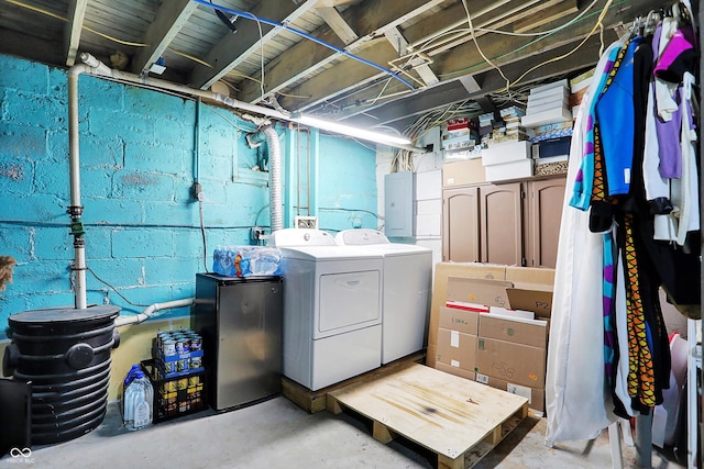 unfinished basement featuring refrigerator, electric panel, and washing machine and clothes dryer