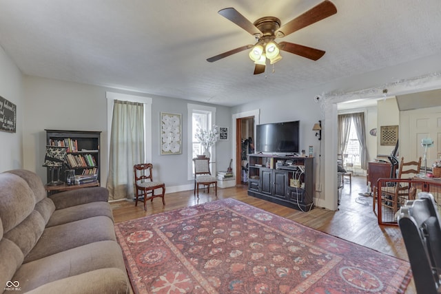 living room with ceiling fan, a textured ceiling, and light wood-type flooring