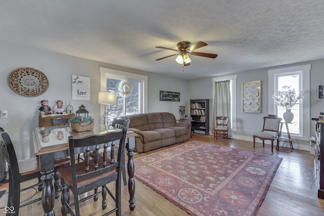 living room featuring ceiling fan, hardwood / wood-style flooring, and a textured ceiling