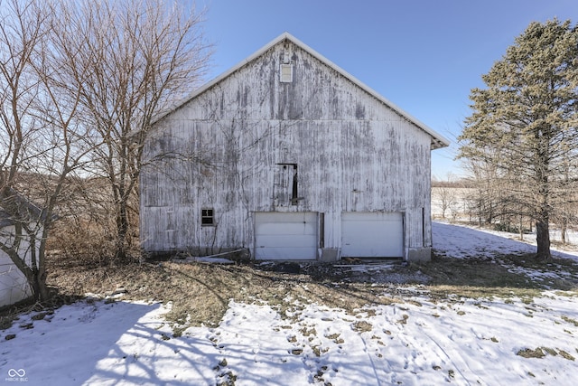 view of snowy exterior featuring a garage and an outbuilding