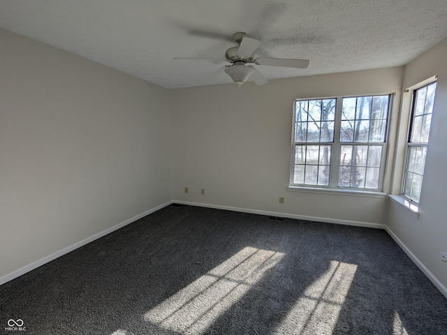 unfurnished room featuring dark colored carpet, ceiling fan, and a textured ceiling