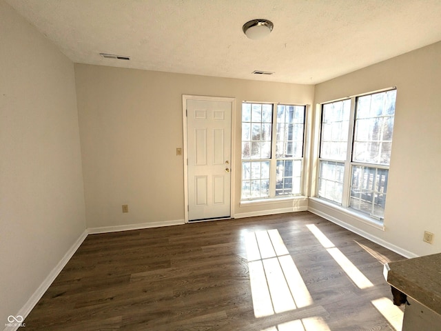 entryway with dark wood-type flooring and a textured ceiling