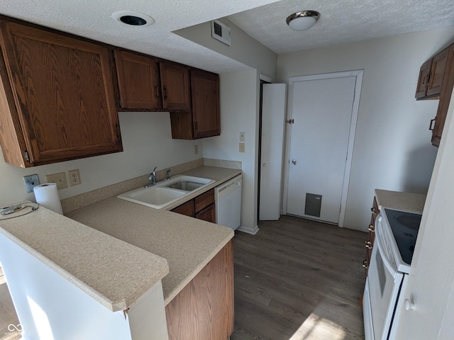 kitchen featuring sink, hardwood / wood-style flooring, white appliances, kitchen peninsula, and a textured ceiling