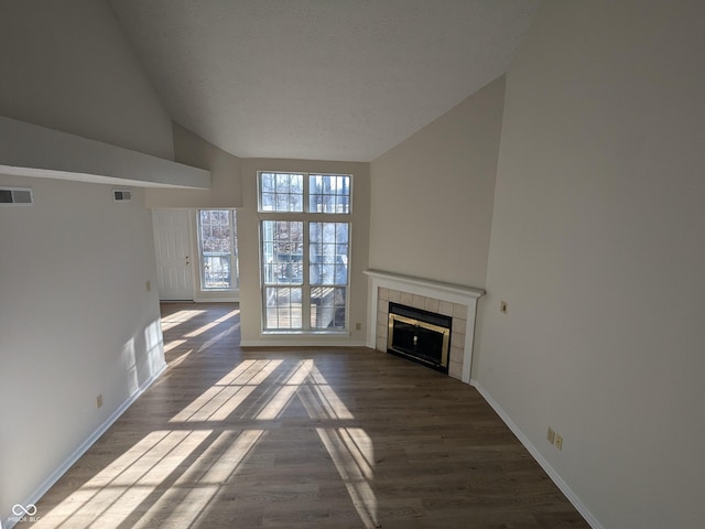 unfurnished living room with a tile fireplace, wood-type flooring, a textured ceiling, and high vaulted ceiling