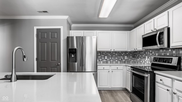 kitchen featuring stainless steel appliances, white cabinetry, and decorative backsplash