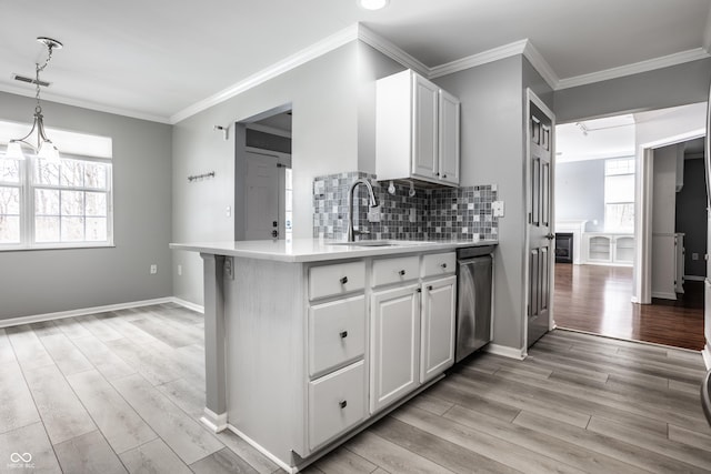 kitchen with tasteful backsplash, white cabinetry, hanging light fixtures, stainless steel dishwasher, and kitchen peninsula