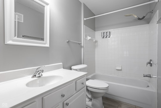 full bathroom with tiled shower / bath, vanity, and toilet