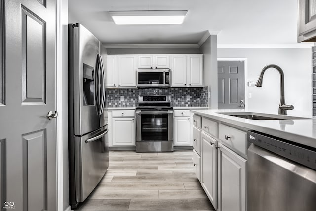 kitchen with stainless steel appliances, sink, decorative backsplash, and white cabinets