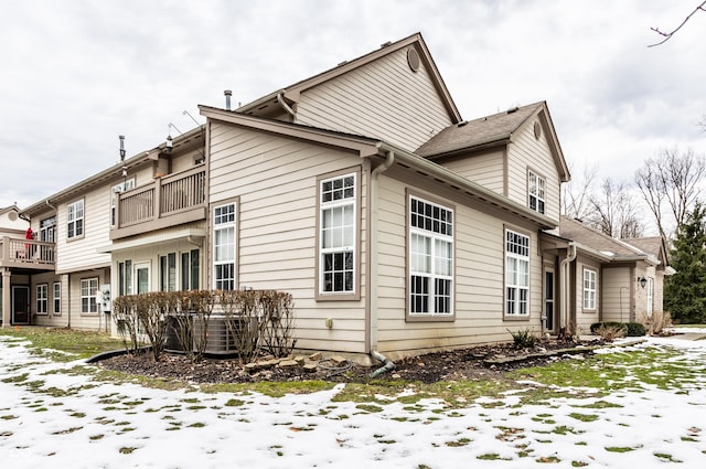 snow covered property with central AC and a balcony