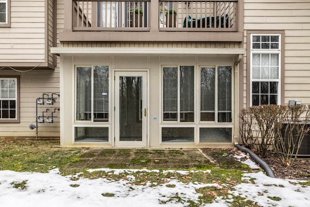 snow covered property entrance with a balcony