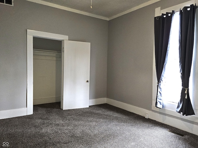 unfurnished bedroom featuring crown molding, dark carpet, and multiple windows